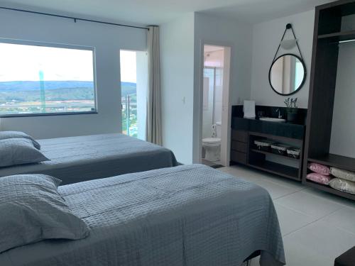 1 Schlafzimmer mit 2 Betten, einem Spiegel und einem Fenster in der Unterkunft Apartamento MIRANTE DE ESCARPAS 1804 in Capitólio