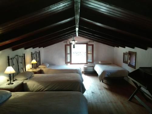 1 dormitorio con 4 camas y ventana en Casa Rural Higuera Morales, en Mocanal