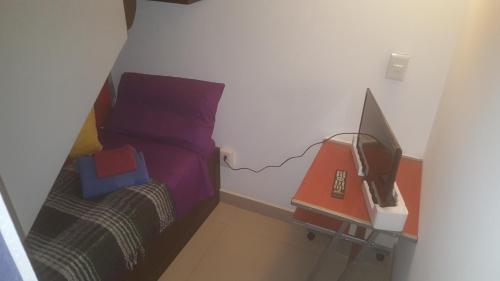 a small bedroom with a bed and a desk with a computer at Division del Norte Rooms in Mexico City