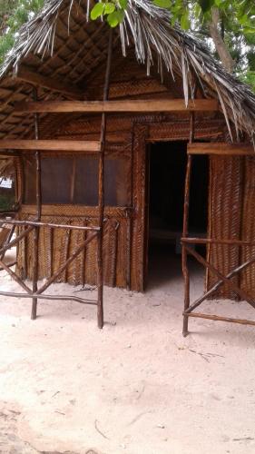 a hut with a straw roof on the beach at Magharibi House in Nungwi