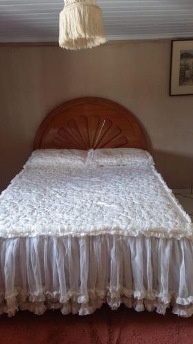 ein weißes Bett mit einem Kopfteil aus Holz im Schlafzimmer in der Unterkunft Chácara Pôr do Sol in Caparaó Velho