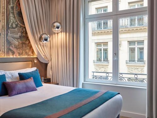 Un dormitorio con una cama y una ventana grande. en Hotel Indigo Paris - Opera by IHG, en París