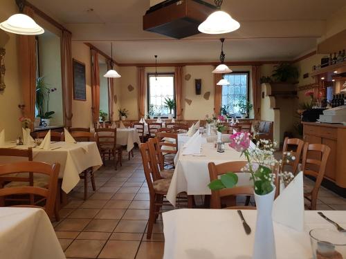 ein Restaurant mit Tischen und Stühlen, weißen Tischen und Blumen in der Unterkunft Landgasthaus Klosterhof in Fischbach