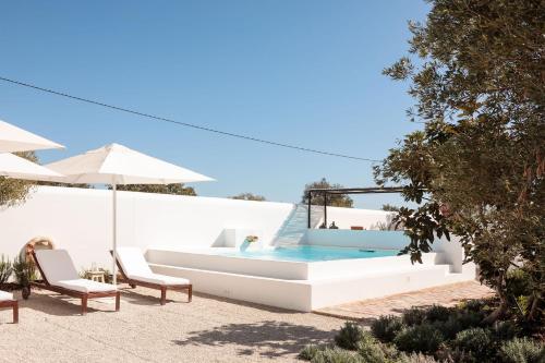 a pool with two chairs and an umbrella at Hospedaria in Alvisquer