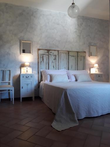 a bedroom with a large white bed with two lamps at Agriturismo L'Essiccatoio in Corgna