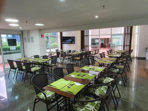 a dining room with tables and chairs with green napkins at Beach Class Exclusive in Fortaleza