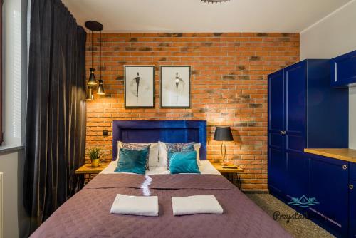 a bedroom with a blue bed and a brick wall at Przystań Stegna in Stegna