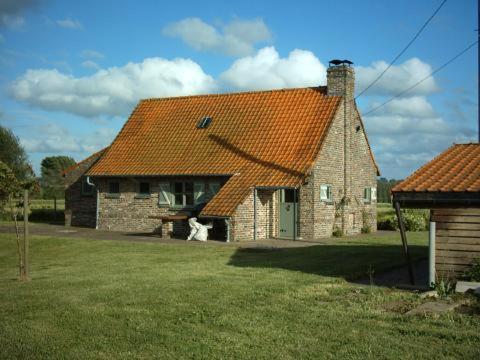 a brick house with an orange roof on a field at Huis Den Keibilk in Heuvelland