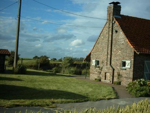 an old brick house with a grass yard next to it at Huis Den Keibilk in Heuvelland