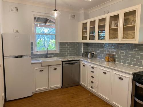 a kitchen with white cabinets and a white refrigerator at Avoca House - Gorgeous Federation Home in Mudgee
