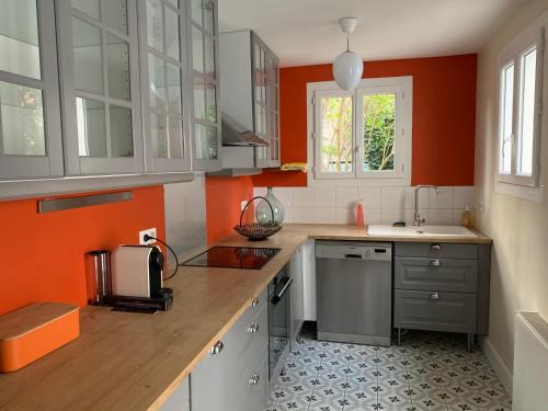 eine Küche mit orangefarbenen Wänden und Holzoberflächen in der Unterkunft La Villégiature in Vichy