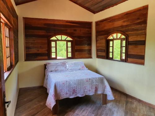 a bedroom with a bed and two windows at Recanto casa amarela in Miguel Pereira