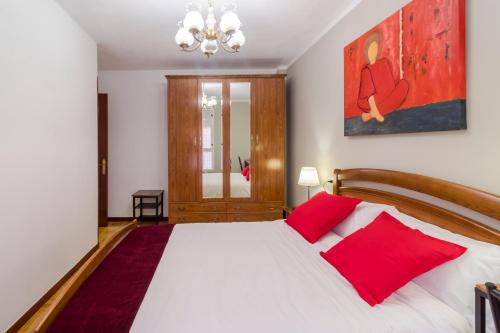 a bedroom with a large white bed with red pillows at Apartamento Vital Aza in Pola de Lena