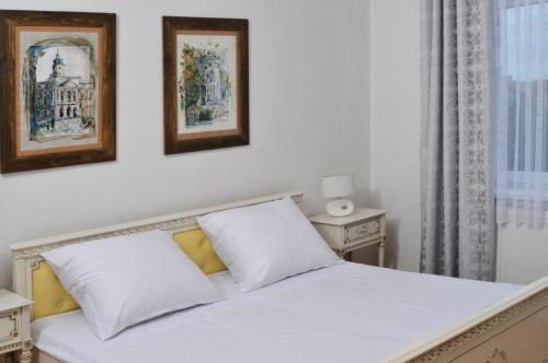 カリシュにあるPrzestronny Apartamentの白いベッド1台、壁に2枚の写真が飾られたベッドルーム1室