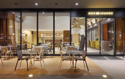 a restaurant with tables and chairs in front of a store at Hotel Nox in Ljubljana