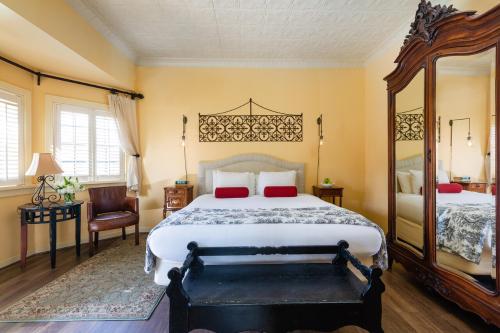 a bedroom with a large bed and a large mirror at Maison Fleurie, A Four Sisters Inn in Yountville