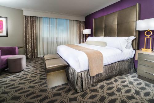 a hotel room with a large bed and a purple wall at Crowne Plaza Saddle Brook by IHG in Saddle Brook