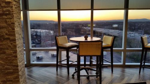 a table and chairs in a room with a large window at Crowne Plaza Saddle Brook by IHG in Saddle Brook