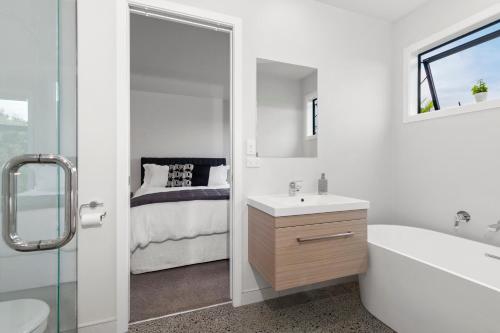 a bathroom with a tub and a sink and a bed at Stylish Villa Escape - Matakana Holiday Home in Matakana