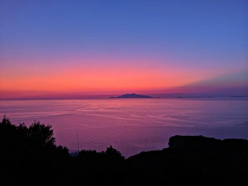a sunset over the ocean with a mountain in the distance at B&B La Danza del Mare in Anacapri
