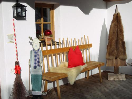 a wooden bench with red pillows and a christmas tree at Alpenferienwohnung Strickner in Neustift im Stubaital