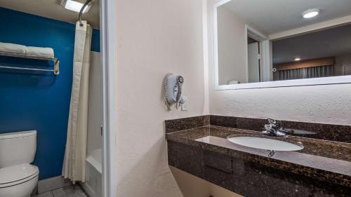 a bathroom with a sink and a toilet and a mirror at SureStay Plus Hotel by Best Western Hesperia in Hesperia