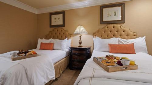 two beds in a hotel room with a tray of food at Best Western Plus Sunset Plaza Hotel in Los Angeles