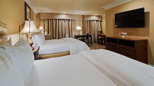 a hotel room with two beds and a flat screen tv at Best Western Plus Sunset Plaza Hotel in Los Angeles