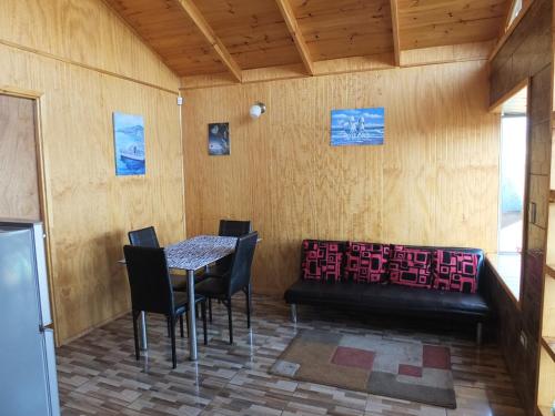 una habitación con una mesa y sillas y un sofá en Cabañas Vista Hermosa, en El Quisco