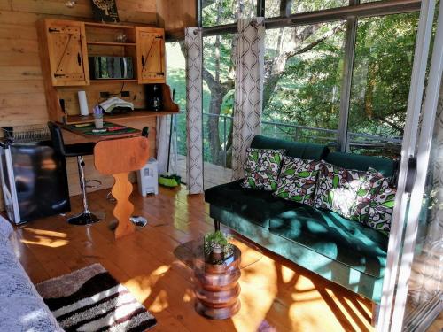 a living room with a green couch and a table at Cabaña treehouse Mountain View in San Isidro