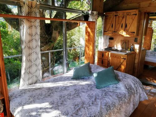 1 dormitorio con 1 cama frente a una ventana en Cabaña treehouse Mountain View, en San Isidro