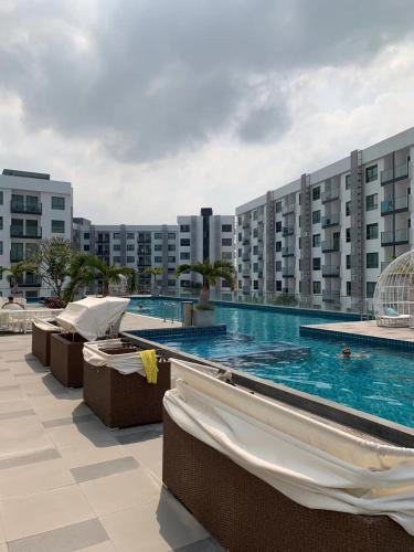 a swimming pool with chairs and buildings in the background at 2BDR in Water Resort close to WalkingStreet in Pattaya South