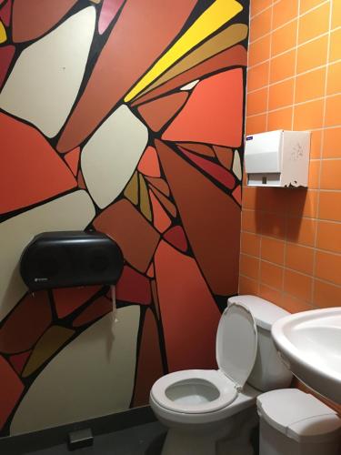 a bathroom with a toilet and a painting on the wall at Auberge Alternative in Montréal
