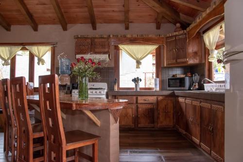 una cocina con armarios de madera y una mesa con sillas. en Cabaña Ensueño, en Mazamitla