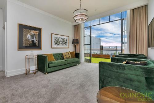 a living room with a green couch and a large window at QV Glamour 2 Bedroom Apt with Carpark - 758 in Auckland
