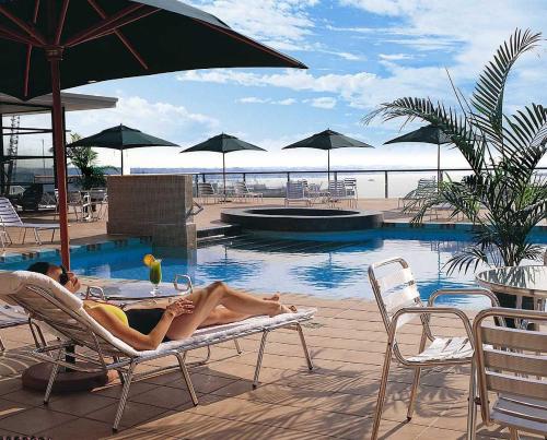 a woman laying on a chair next to a swimming pool at QV Glamour 2 Bedroom Apt with Carpark - 758 in Auckland