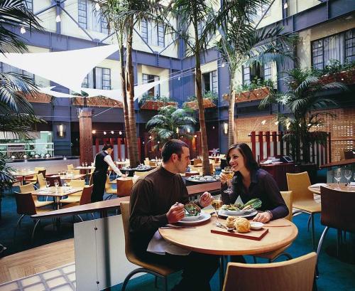 a man and woman sitting at a table in a restaurant at QV Glamour 2 Bedroom Apt with Carpark - 758 in Auckland