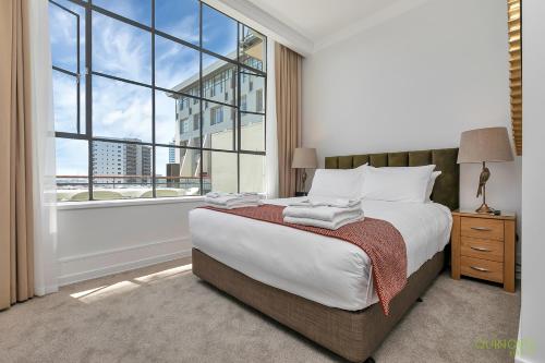 een slaapkamer met een bed en een groot raam bij QV Glamour 2 Bedroom Apt with Carpark - 758 in Auckland