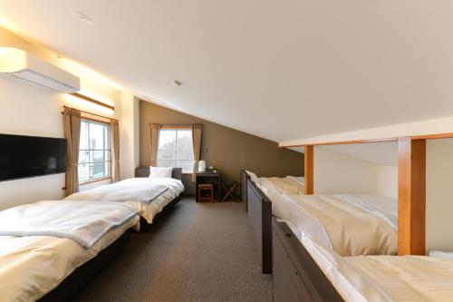 a room with three beds and a tv and a desk at G-SQUARE in Yamagata