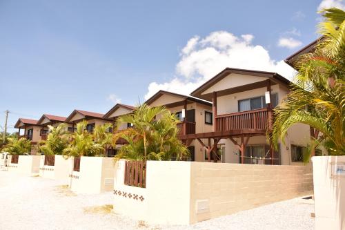 a row of houses on the beach with palm trees at Churaumi Village in Motobu