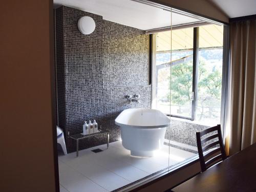 ein Bad mit einer Badewanne und einem großen Fenster in der Unterkunft Nagaragawa Seiryu Hotel in Gifu