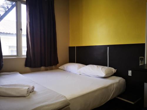 two beds in a bedroom with a yellow wall at Dragon Door Hotel in Sitiawan