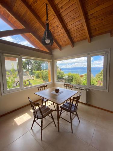 a dining room with a table and chairs and windows at Andalue in San Carlos de Bariloche