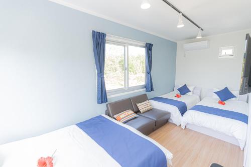een kamer met 3 bedden, een bank en een raam bij Regina Ishigaki in Ishigaki Island