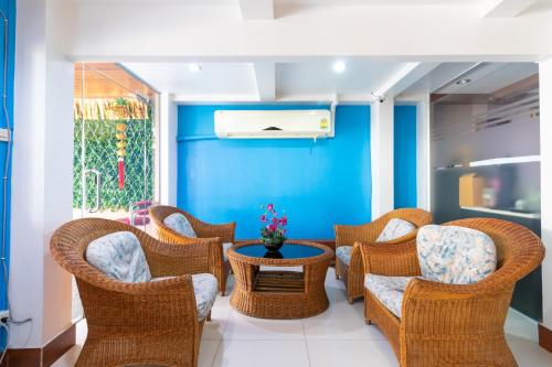 a room with wicker chairs and a table and a blue wall at Thipurai Annex Hotel in Hua Hin
