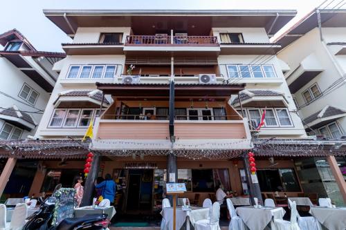 a building with tables and chairs in front of it at Thipurai Annex Hotel in Hua Hin