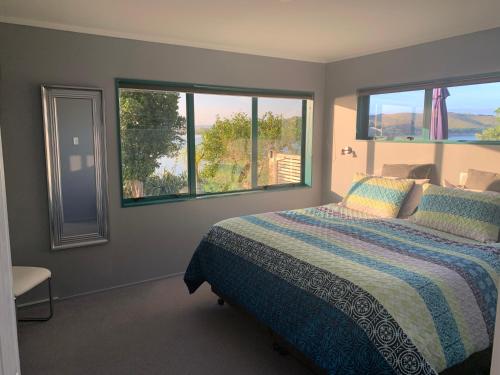 a bedroom with a bed and two windows at Beach Lane Apartment in Whangarei