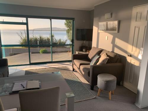 a living room with a couch and a view of the ocean at Beach Lane Apartment in Whangarei