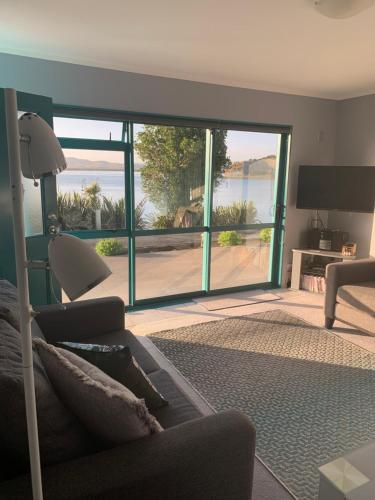 a living room with a couch and a view of the ocean at Beach Lane Apartment in Whangarei