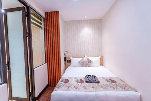a bedroom with a white bed with a bag on it at MOMIZI Hotel HAI PHONG in Hai Phong